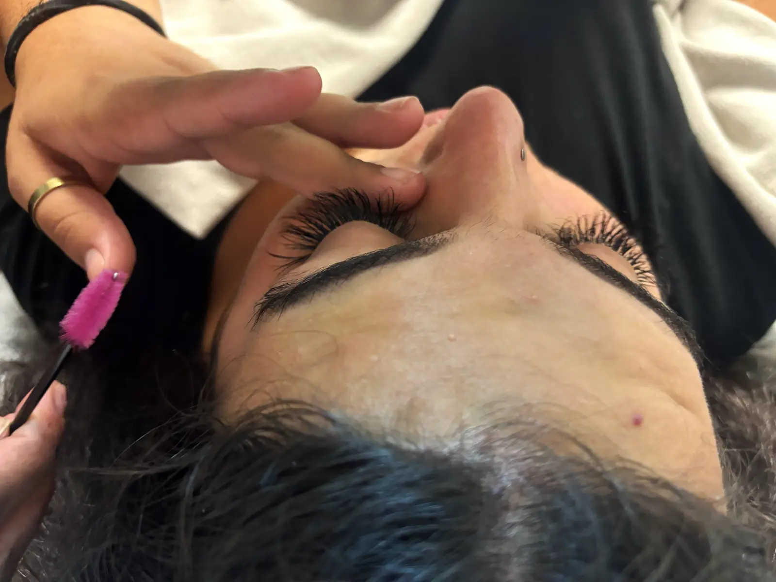 Estudiante de estética aplicando extensiones de pestañas individuales, acercamiento