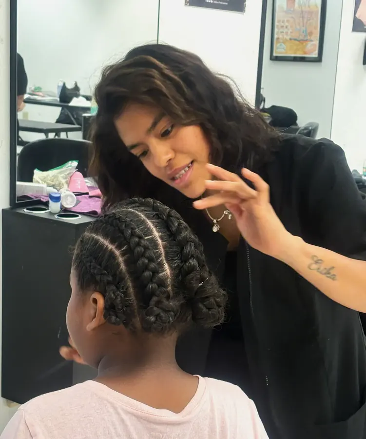 Estudiante de estilismo de cabello practicando trenzas en la clínica de estudiantes