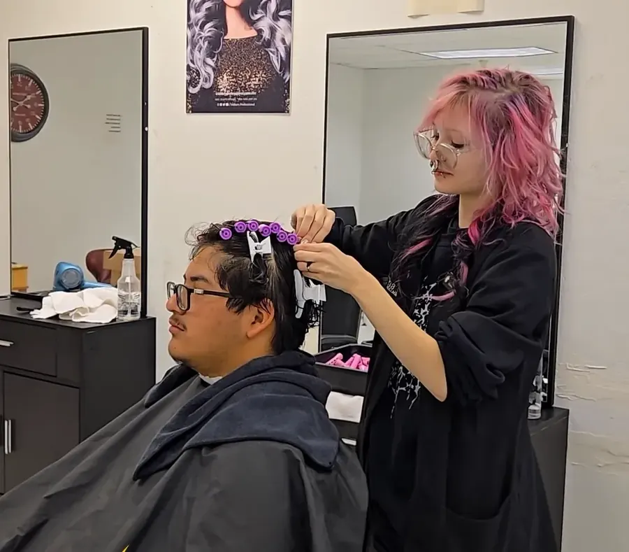 Una alumna de cosmetología coloca rulos de permanente durante una práctica de clínica estudiantil en Mima's Beauty College, en Phoenix, Arizona