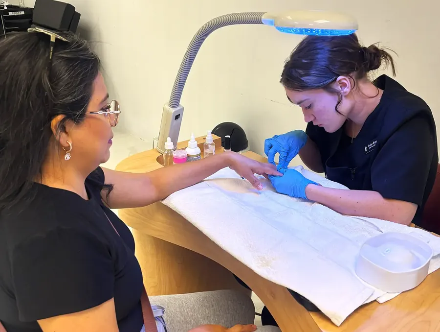 Estudiante de tecnología de uñas realizando una manicura en la clínica de estudiantes