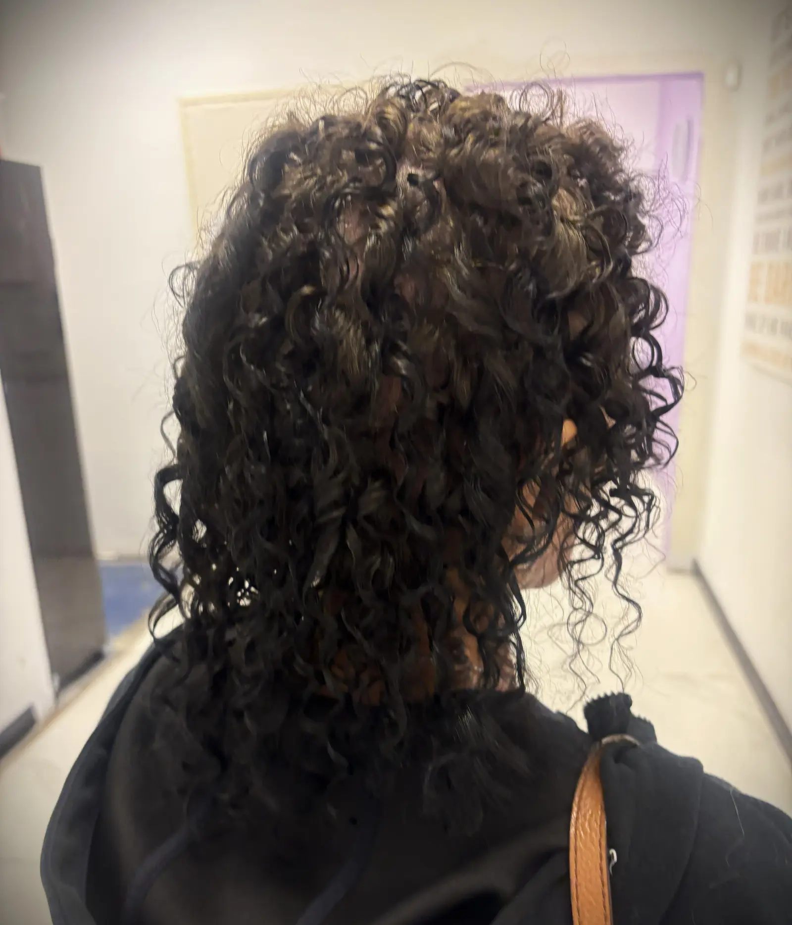 Resultado de permanente con rizos voluminosos en cabello largo y oscuro, práctica de estudiante de peinado