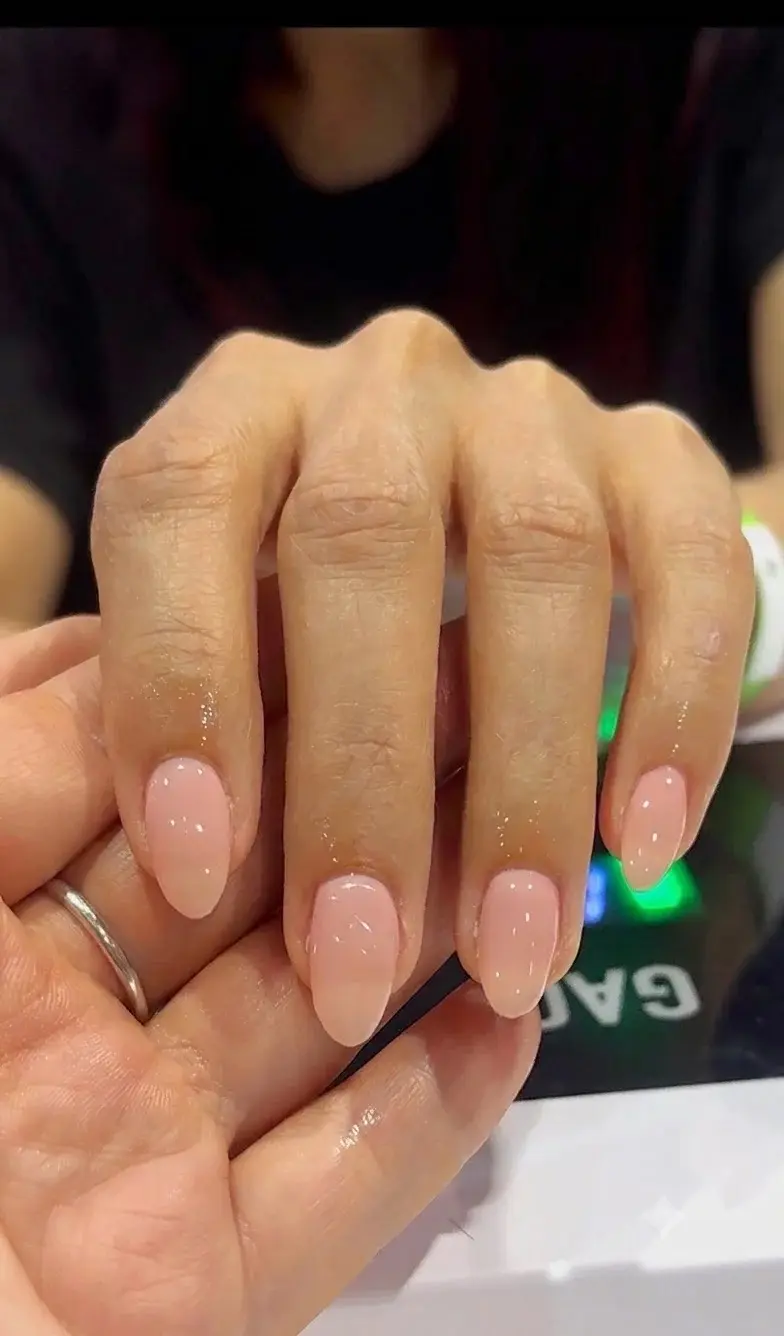Manicure de gel rosa natural en uñas forma ovalada, trabajo de estudiante de tecnología de uñas