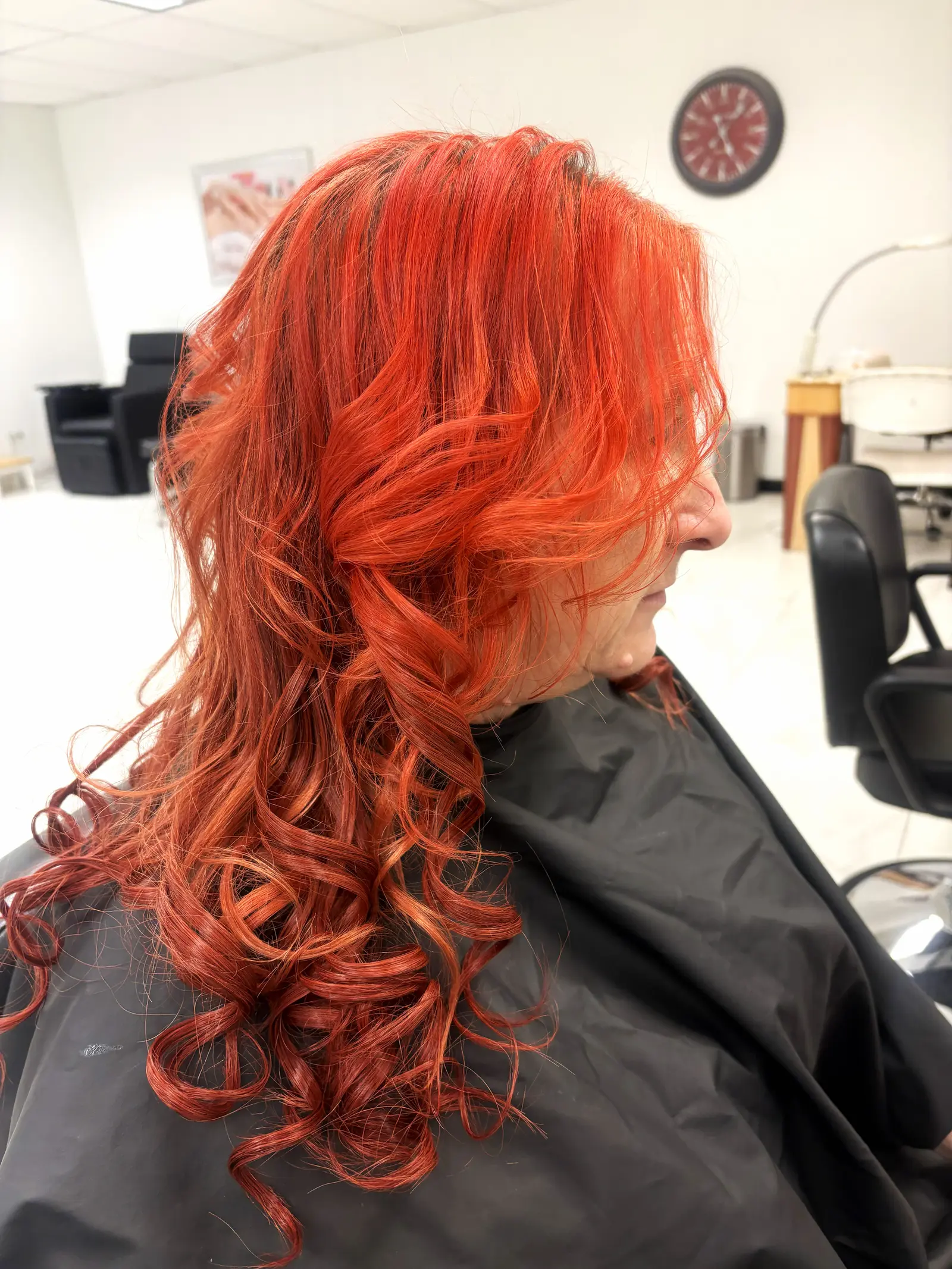 Color de cabello rojo vivo con rizos, práctica de color de estudiante de cosmetología